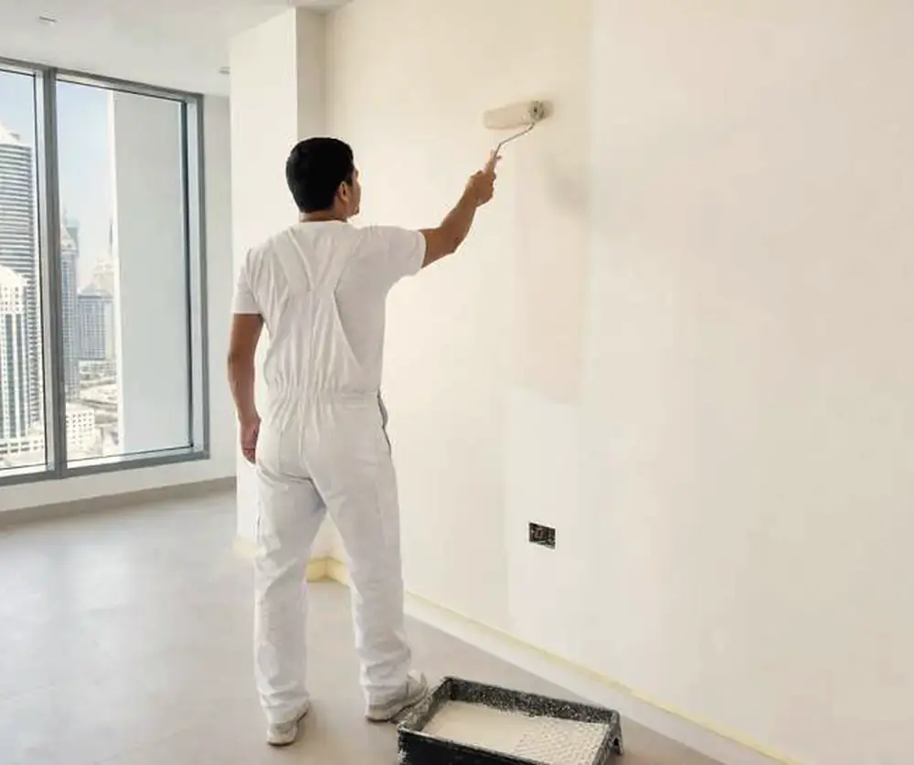 Painter rolling a fresh coat on a bright apartment wall